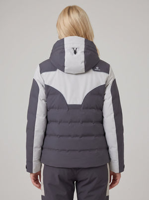 A woman viewed from the back wearing a color-blocked heated puffer ski jacket in dark gray and light gray, paired with matching gray pants with light gray side stripes.