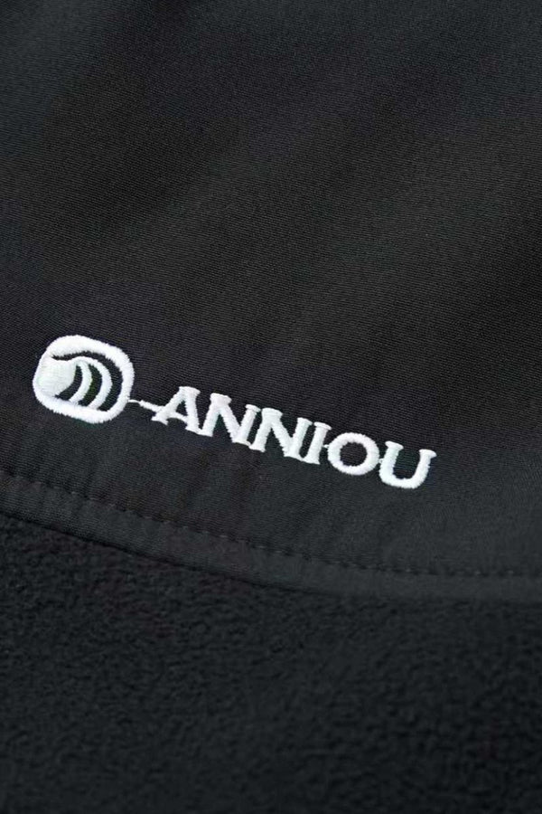Close-up of a black fabric with 'Anniou' logo embroidered on it.