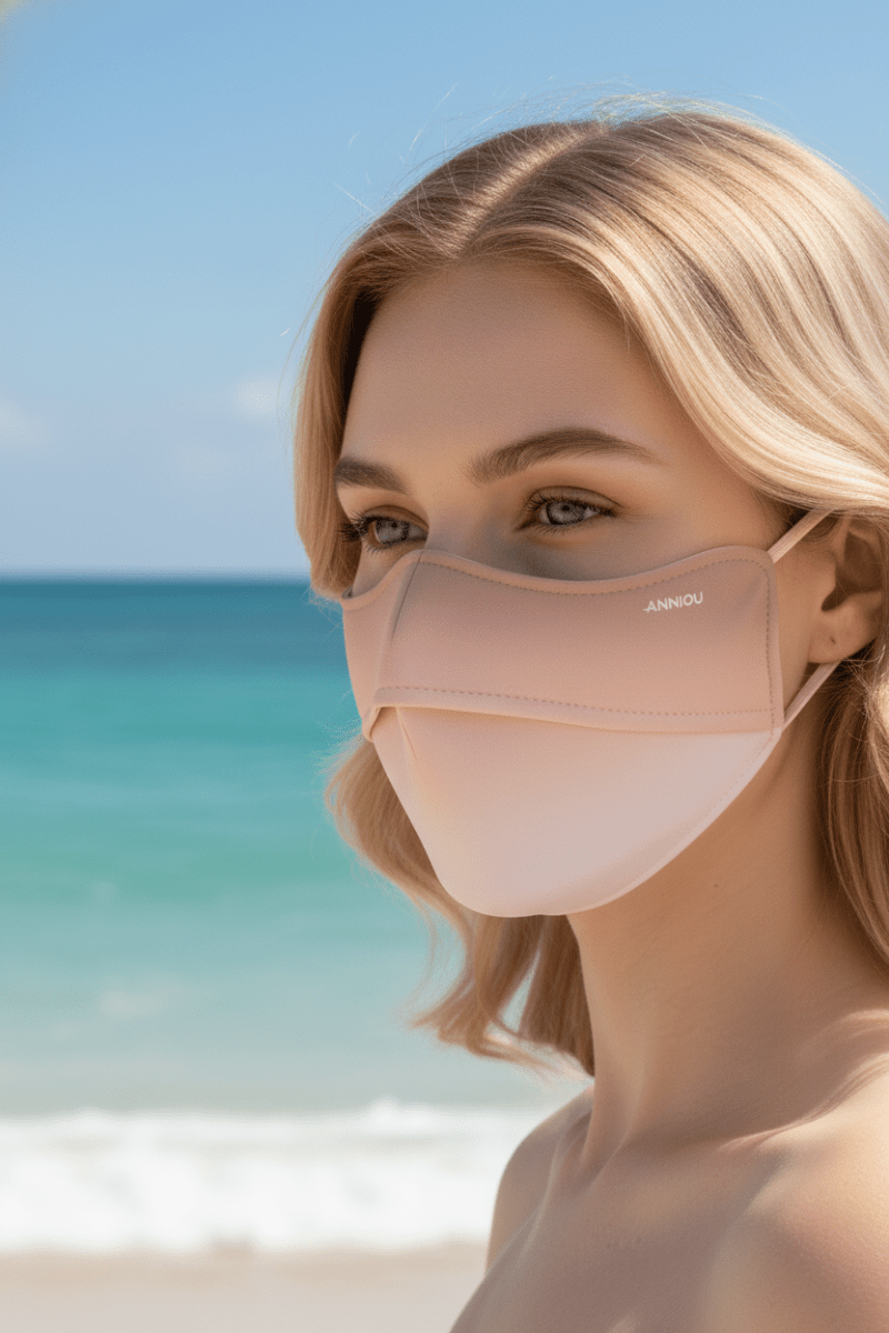 Woman wearing a apricot face mask with a beach in the background