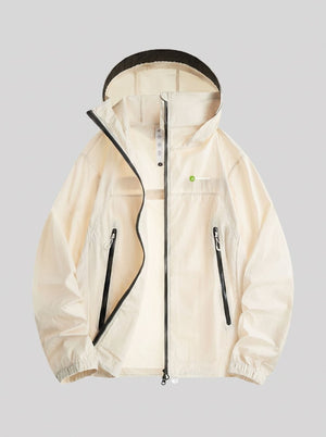 A light cream-colored hooded jacket with black zipper details and a small green circular logo on the chest, displayed against a solid gray background.