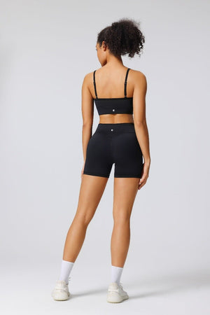 Woman showing the back of the #black adjustable seamless sports bra and black butt lift yoga shorts with an Anniou logo 