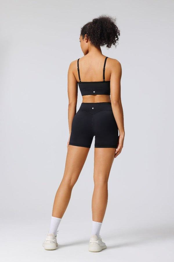 Woman showing the back of the #black adjustable seamless sports bra and black butt lift yoga shorts with an Anniou logo 