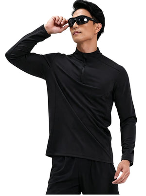 Male model in #black half-zip long sleeve sports top adjusting sunglasses, plain  background.