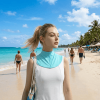 The woman is wearing a blue ice silk sun protection neck gaiter, with a beach in the background.