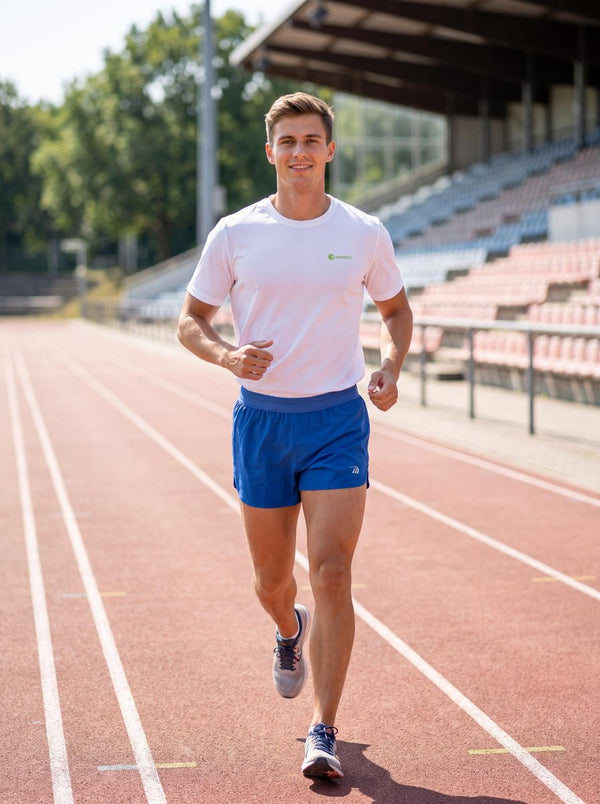 A man wearing a Anniou white sports T-shirt and ultra-lightweight quick-drying blue sports shorts is running on an outdoor track.