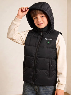 A boy wearing a black heated hooded puffer vest over a cream long-sleeve shirt and blue jeans.