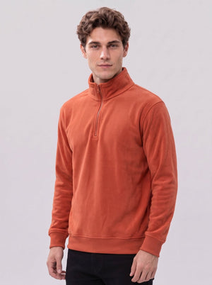 Handsome young male model in #brickred half zip fleece sweater, three-quarter side standing, arms naturally hanging down, light gray background, men warm fleece top
