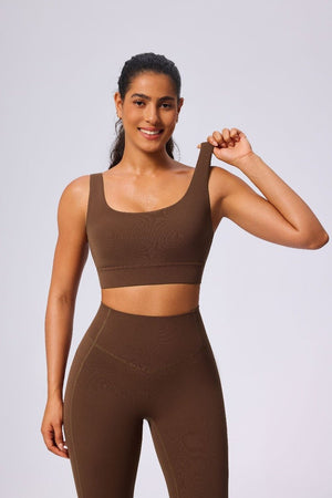 Woman wearing a #brown sports bra and leggings on a light gray background