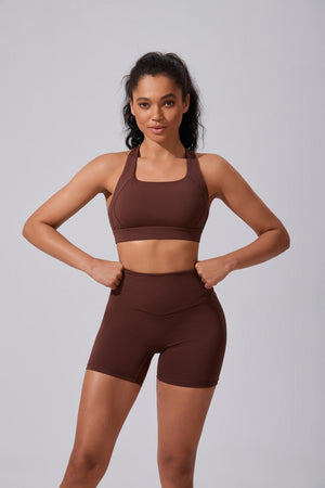Woman wearing a #brown sports bra and high waist yoga shorts set on a gray background