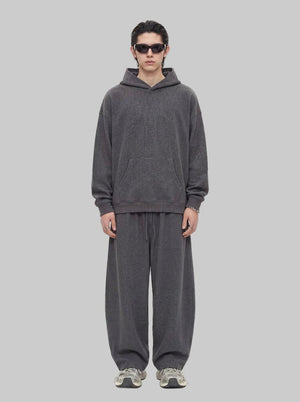 A male model wearing sunglasses stands facing forward against a plain white background, dressed in a #darkgrey waffle-knit hoodie and matching wide-leg sweatpants.