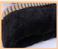 Close-up of black textured fabric with a beige and brown striped pattern hat  in the background.