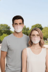 Two people wearing face masks outdoors with a clear sky and greenery in the background