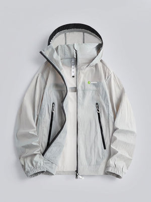 A light gray hooded windbreaker jacket with black zipper details and a small green and white logo on the left chest, displayed flat against a light gray background.