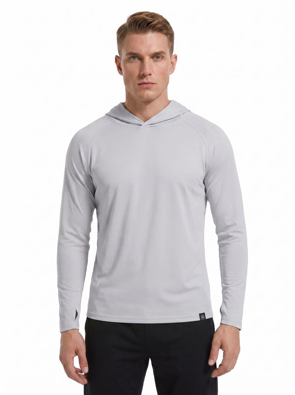 A male model wearing a #grey hooded long-sleeve performance shirt and black athletic pants stands against a plain white background. 