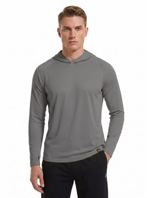 A male model wearing a #grey-1 hooded long-sleeve performance shirt and black athletic pants stands against a plain white background. 