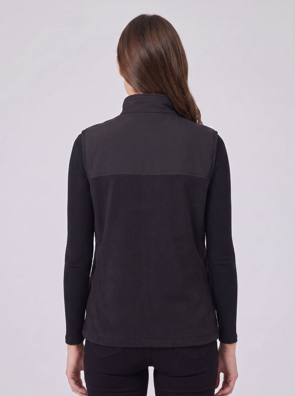 A woman viewed from the back wearing a black long-sleeve quarter-zip fleece vest over a black top, set against a plain light gray studio background.