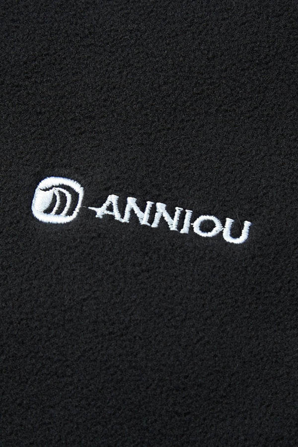 Close-up of a black fabric with 'Anniou' logo embroidered in white.
