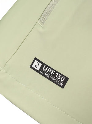 Close-up of a lightgreen fabric item showing a black rectangular label that reads '2 UPF 150 UV PROTECTION' near a zipper.
