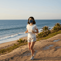 Woman jogging on a beach path with ocean view wearing a upf 50+ face mask