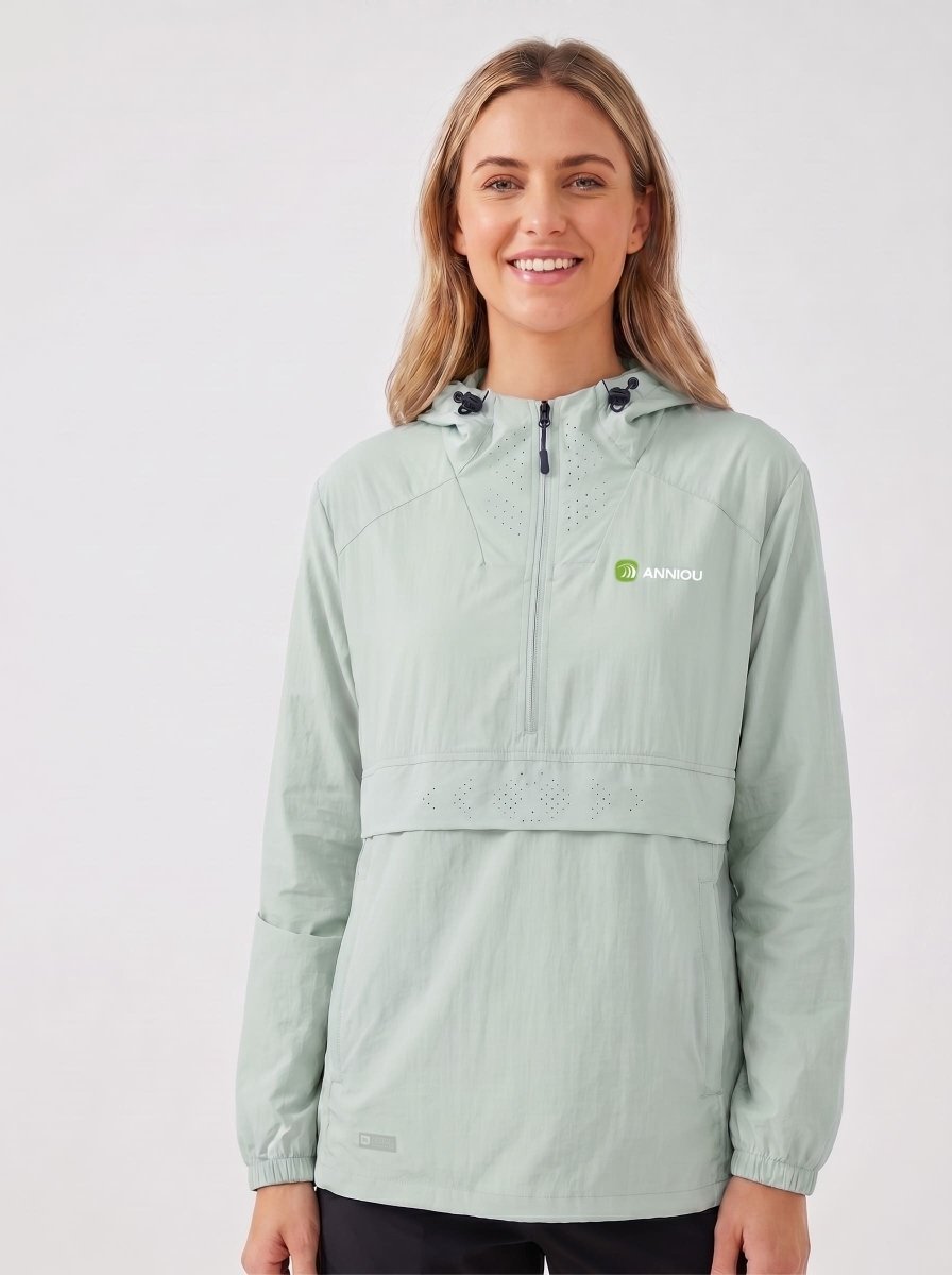 A woman wearing a #lightgreen hooded UV jacket with a half-zip front and a small green and white 'Anniou' logo on the left chest, photographed against a plain light gray studio background.