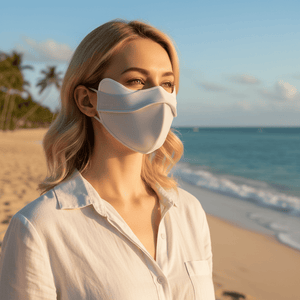 Woman wearing a white face mask on a beach with palm trees and ocean in the background