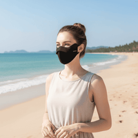 Woman wearing a black face mask on a beach with clear blue water and sky.