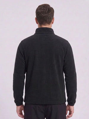 A man viewed from the back wearing a black long-sleeve quarter-zip fleece pullover and dark trousers, set against a plain light gray studio background.