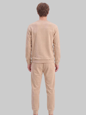 A male model shows the back view of a khaki two-piece tracksuit. The sweatshirt and jogger pants are crafted from diamond jacquard textured fabric. It features a crew neck sweatshirt with ribbed hem and cuffs, paired with matching tapered jogger trousers with ribbed ankle cuffs. 