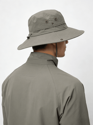 Person wearing a beige wide-brimmed hat and matching jacket on a white background