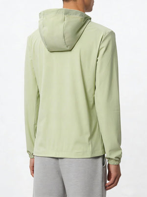 A person shown from the back wearing a #lightgreen hooded jacket and gray sweatpants against a plain white studio background.