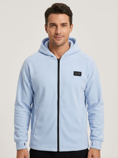 A man wearing a light blue zip-up heated hoodie with a black zipper and a dual controls.