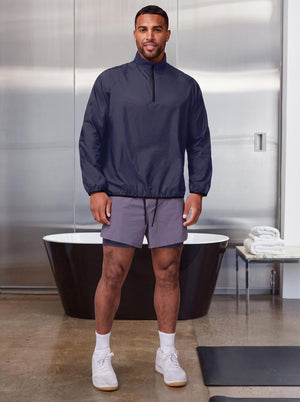 Male model wearing #navy quarter-zip lightweight wind pullover and grey 2-in-1 athletic shorts,