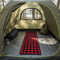 Camping scene with a tent, red checkered electric heated mat, backpack, and camping gear.