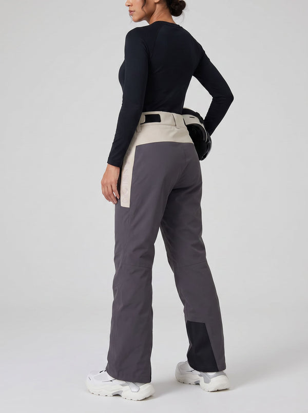 A woman shown from the back wearing colorblock ski pants in dark gray and beige, paired with a black long-sleeve top