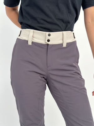 Close-up of a woman wearing gray ski pants with a contrasting off-white waistband and dark buttons