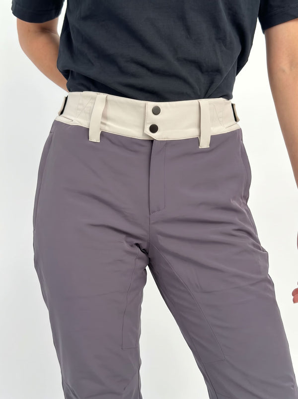 Close-up of a woman wearing gray ski pants with a contrasting off-white waistband and dark buttons