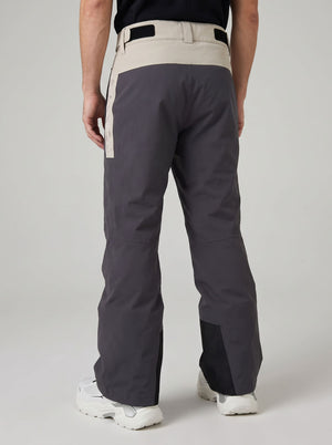 Rear view of a person wearing dark gray heated ski pants with a light beige waistband and side panel, paired with white ski boots