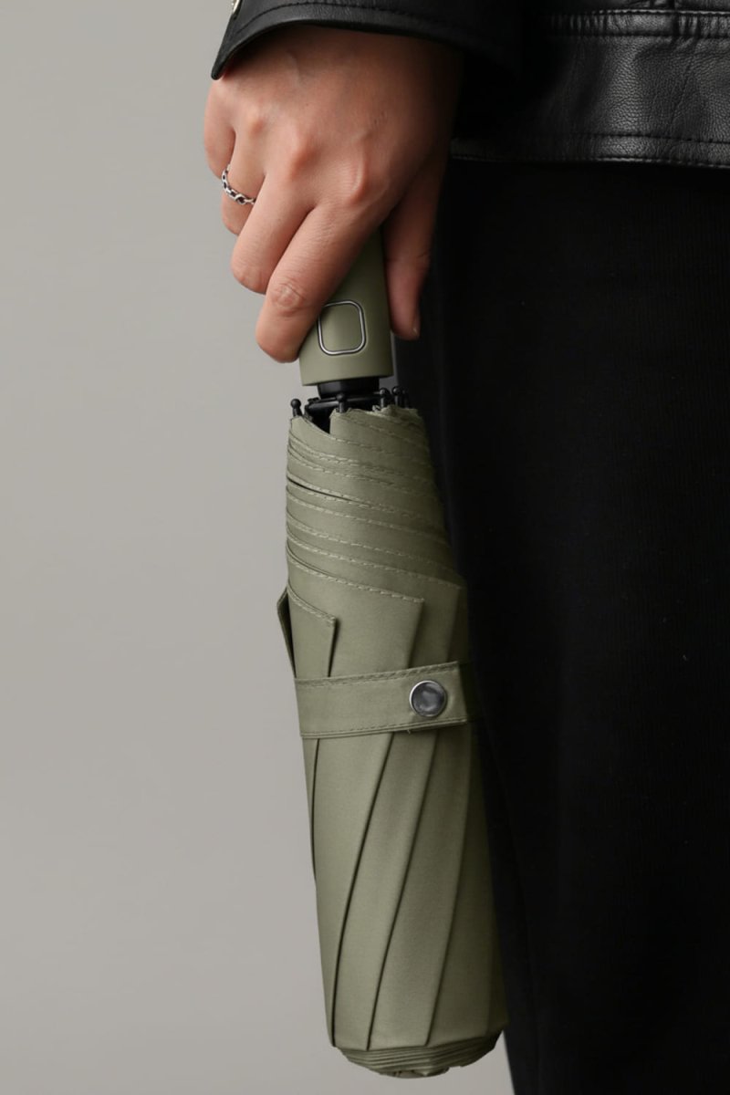 Person holding a green umbrella against a gray background