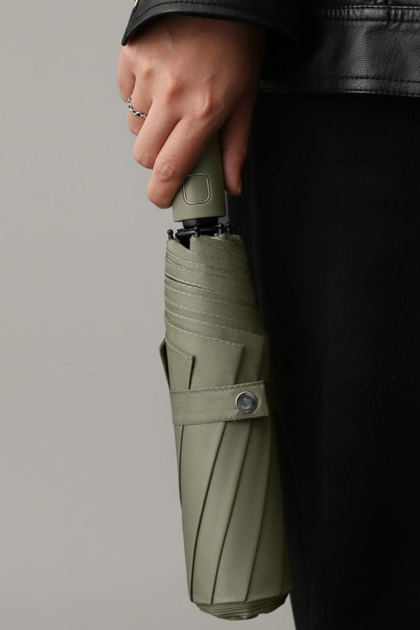 Person holding a green umbrella against a gray background