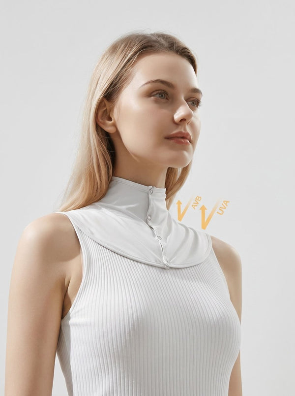 A woman wearing a white ribbed sleeveless top with a high mock neck and front zipper, shown against a light gray studio background.