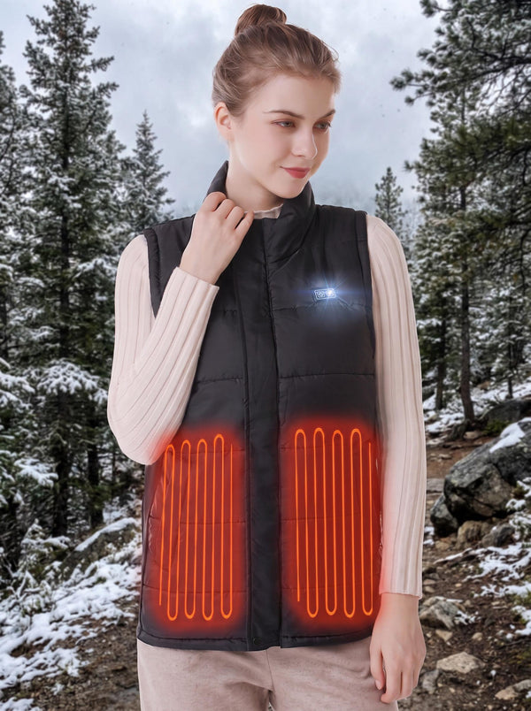young woman wearing black heated vest with glowing orange heating‑zone outlines, snowy pine‑forest outdoor background, adjusting vest collar, LED control button on chest, cold winter mountain scenery.