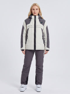 A woman modeling a heated ski jacket and matching ski pants set. The jacket is off-white and dark gray with a black zipper and 'ANNIOU' printed across the chest.