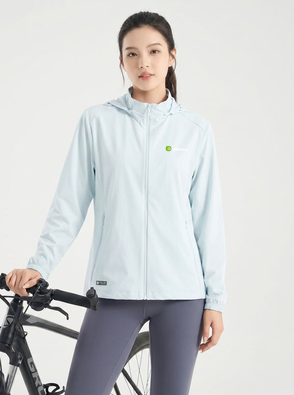 A woman wearing a #glacierblue hooded athletic jacket and dark gray leggings stands next to a black bicycle